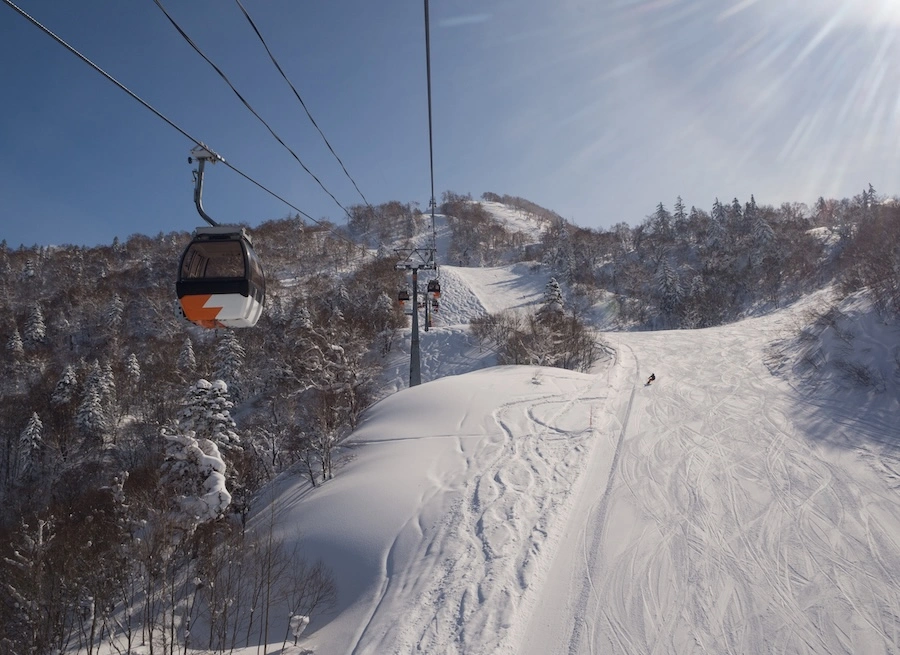 Gondola lift above snow-covered ski runs in Akaigawa, Hokkaido, Japan.