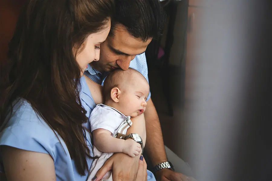 Two parents cradling a sleeping baby.