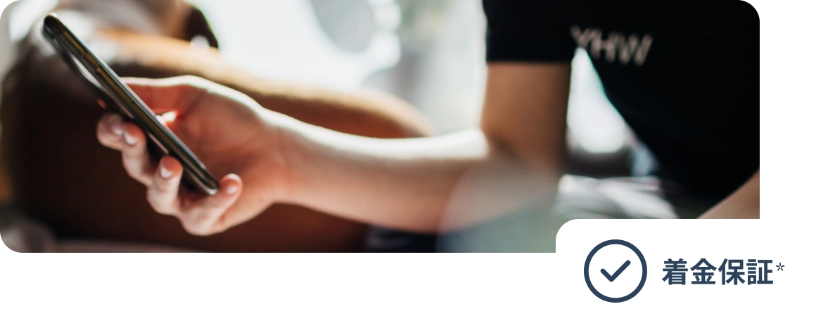 携帯電話を持つユーザー。画像には「着金保証」というテキストが添付されている。