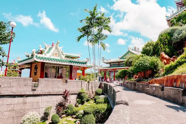 Pathway through temple gardens with traditional architecture and greenery.