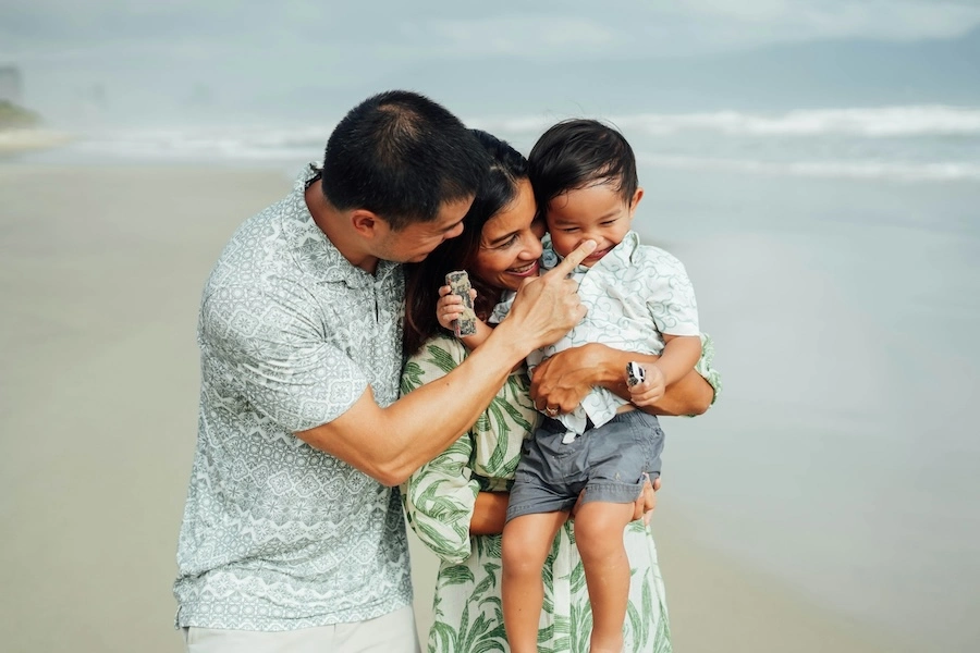 Family smiling and playing together on a beach.