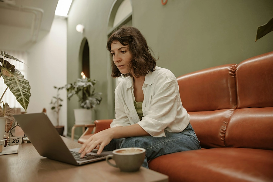 Two people working on laptops together at a table in a bright office setting.