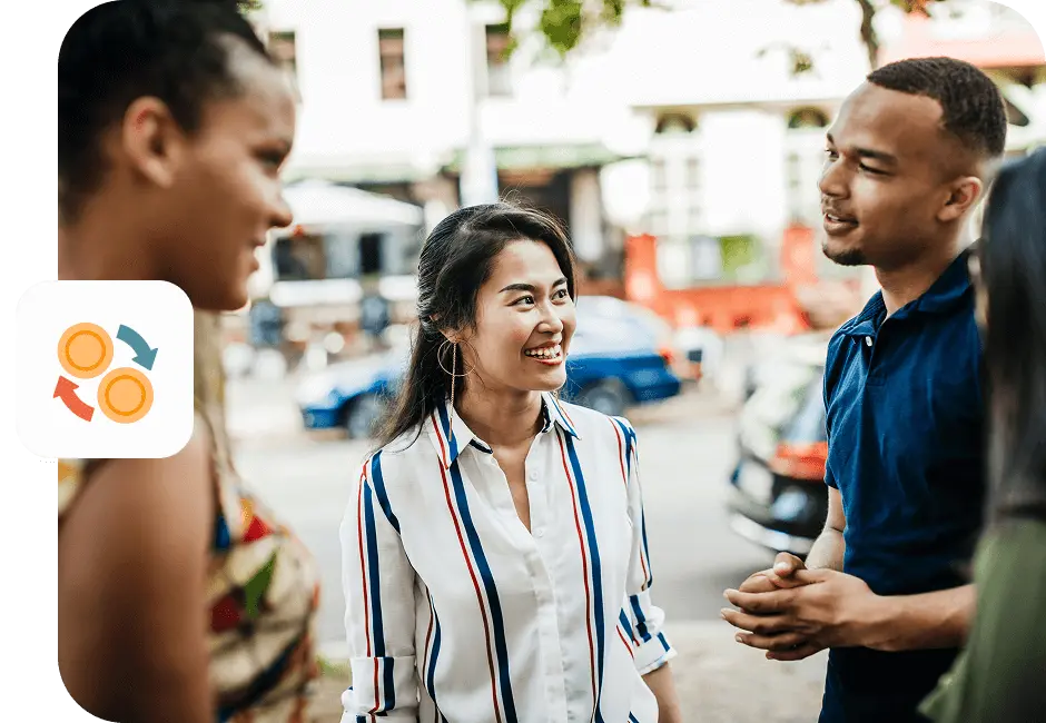 Three friends are smiling and talking together outside on a sunny day.