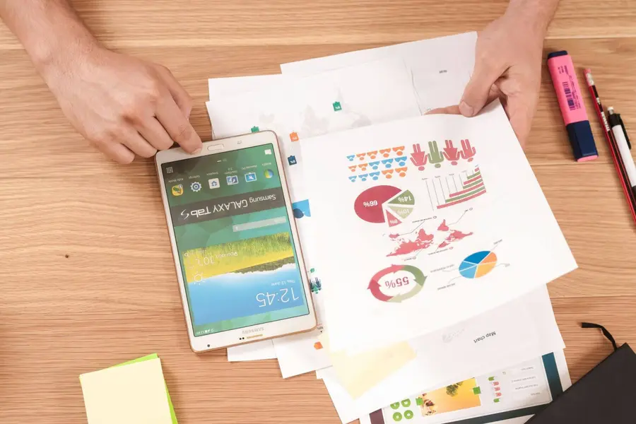 Person holding printed data charts and infographics on a desk.