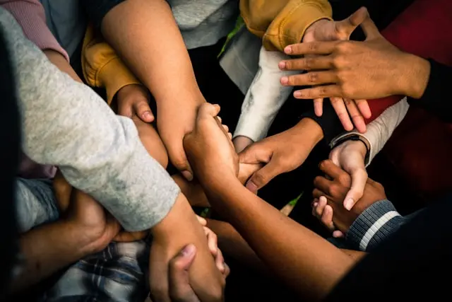 A group of people join hands in a circle.