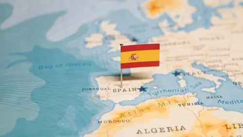 Small Spanish flag pinned on a map highlighting Spain.