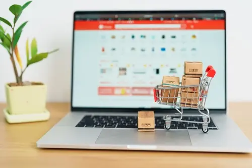 Um carrinho de compras em miniatura com caixas sobre um notebook.