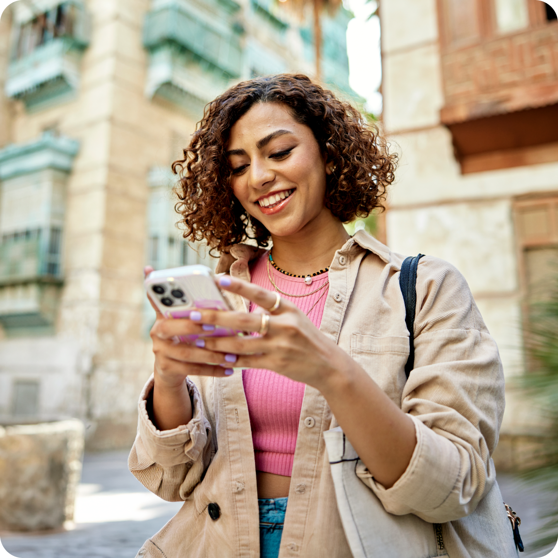 Woman smiling while holding and looking down at her phone.