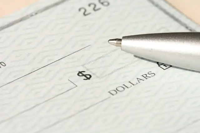 Uma caneta prateada pousada sobre um cheque em branco.