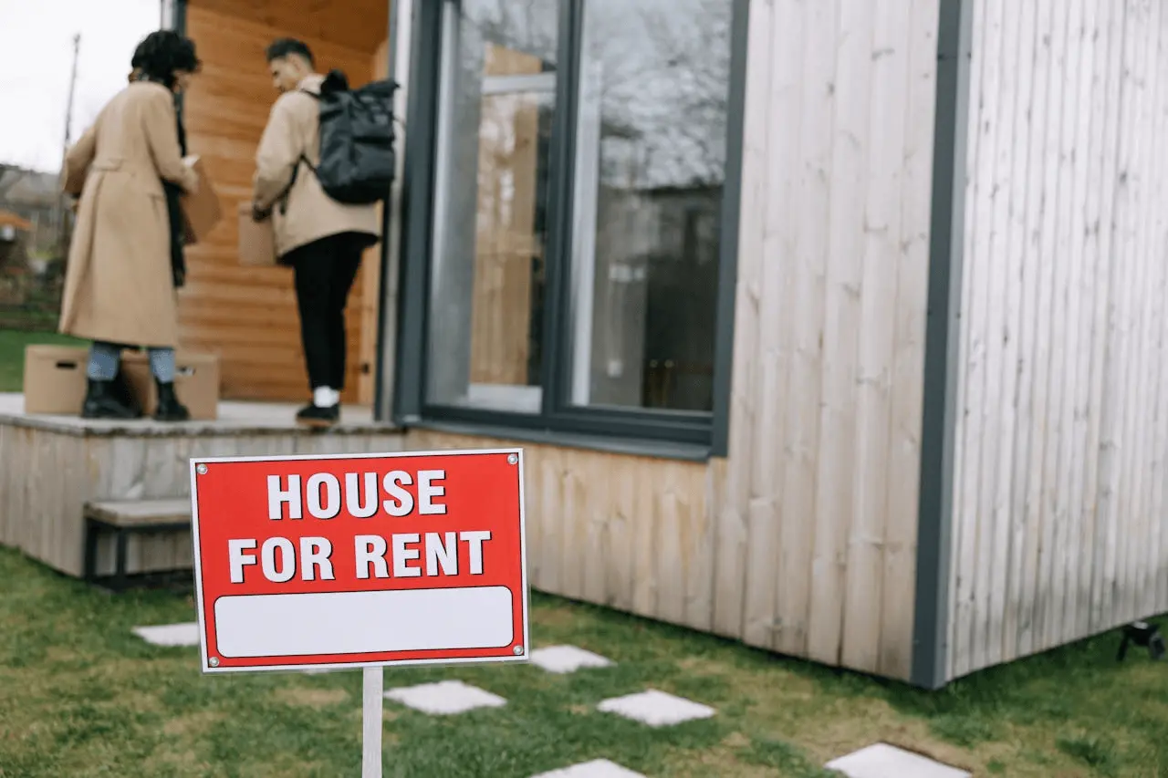 People moving into a house with a "for rent" sign.