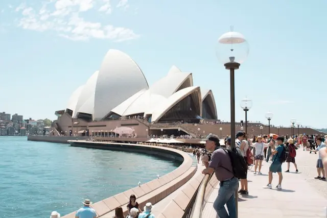 Visitors walking along the harbor near the Sydney Opera House in Australia.