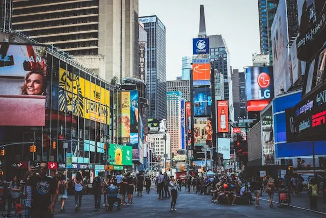 Busy Times Square with people walking among tall buildings and digital billboards.