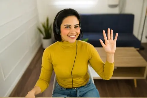 Uma mulher sorridente usando fones de ouvido e acenando.