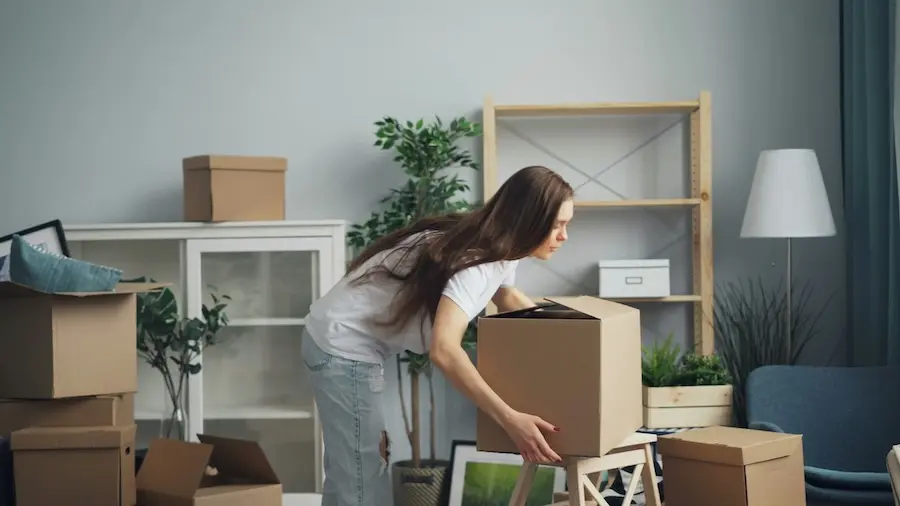 A woman moving boxes in a room.