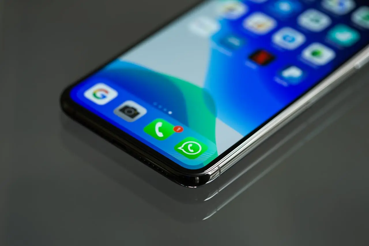Celular sobre una mesa con el ícono de la app de WhatsApp que muestra una insignia de notificación.