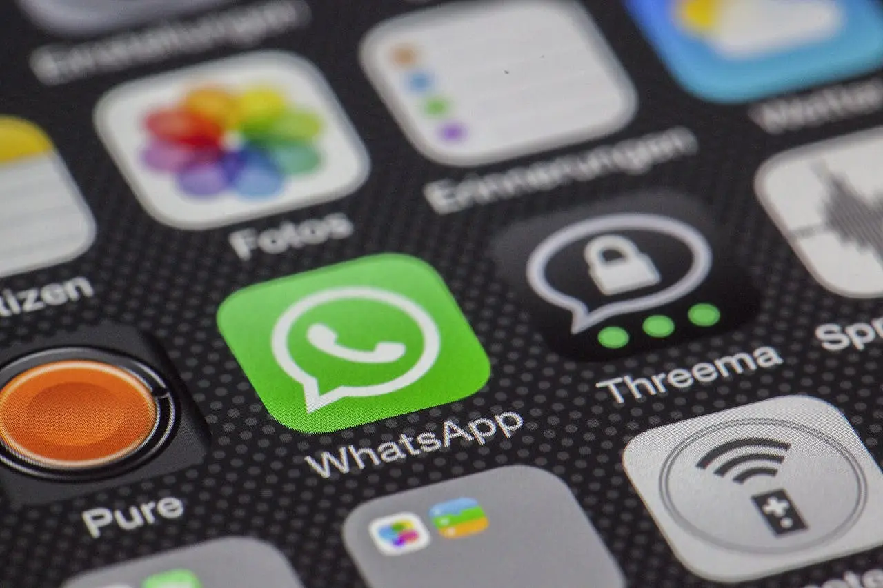 Primer plano de la pantalla de inicio de un celular que muestra el ícono de la app de WhatsApp entre otras apps.
