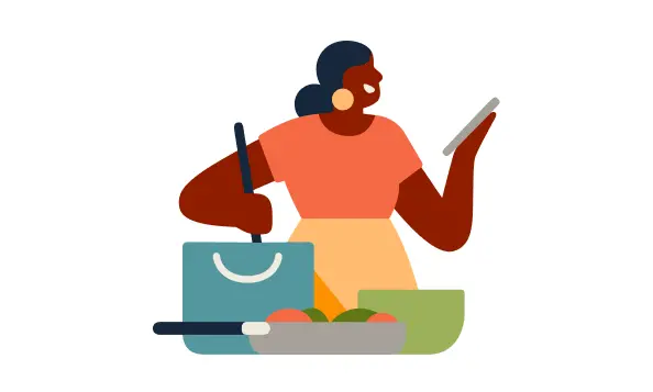 Mujer que cocina en una cocina mientras mira su celular.